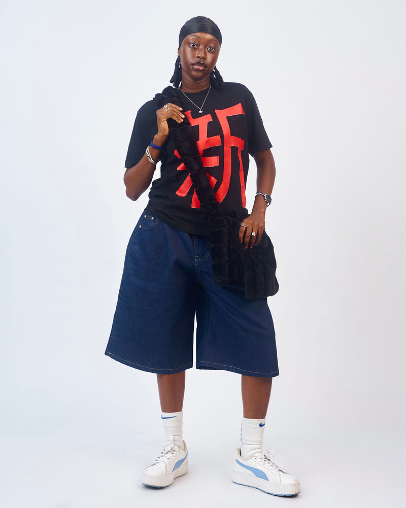 Model wearing a black T-shirt with a red Japanese character and indigo denim shorts