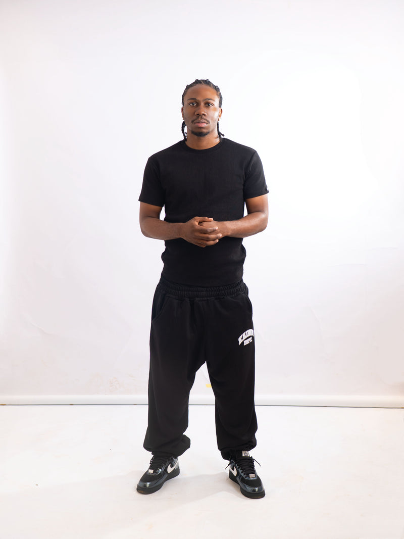 Full-length view of a model wearing the black sweatpants with a black T-shirt