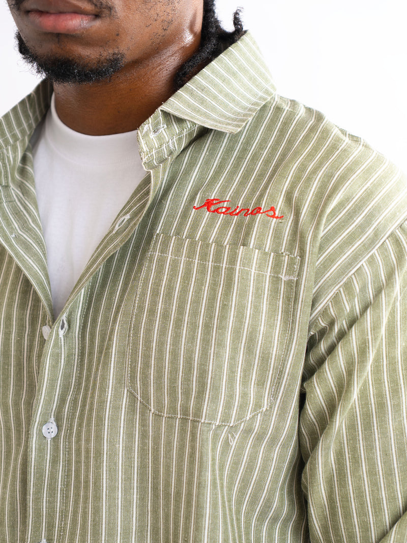 Close-up of the olive and white striped shirt showing the chest pocket and red KAINOS script embroidery